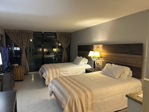 Una habitación de hotel con dos camas, televisión, escritorio y baño.