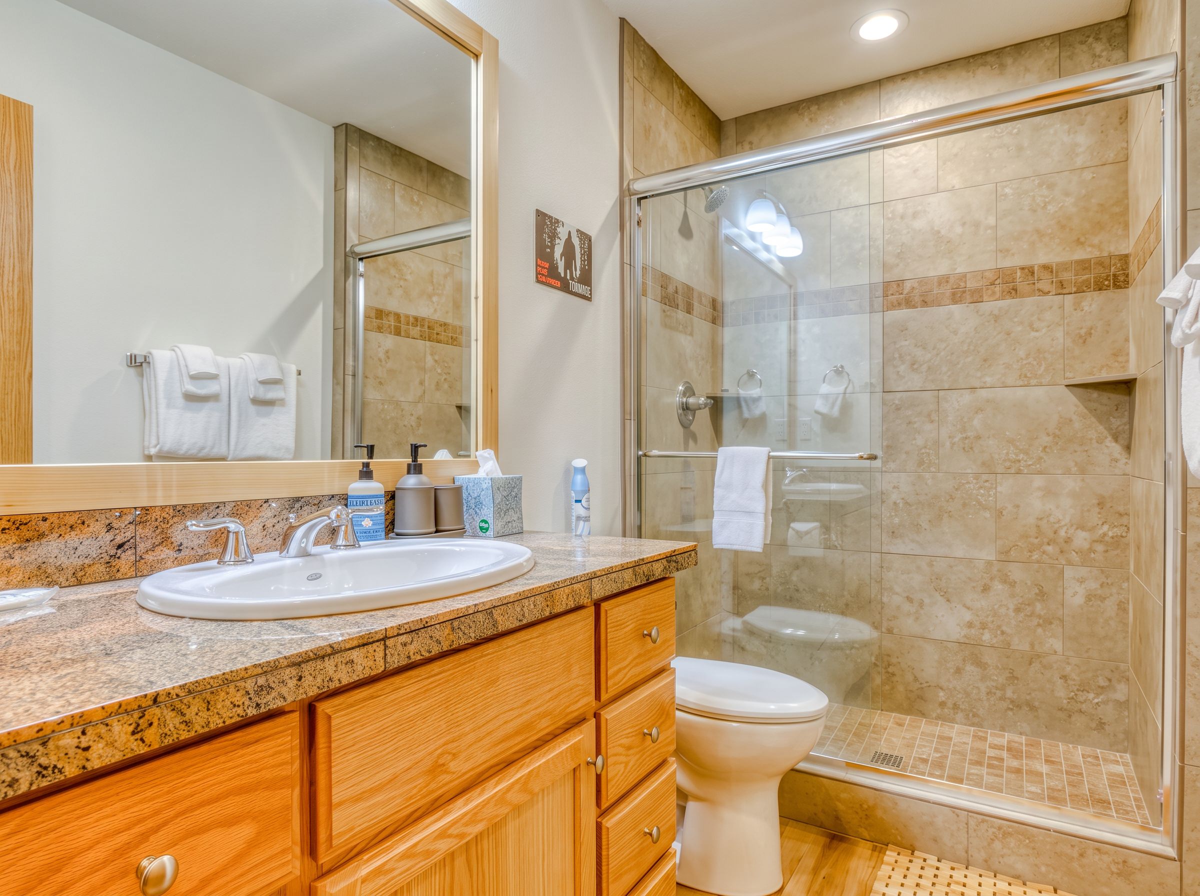 A bathroom with a sink, mirror, and shower.