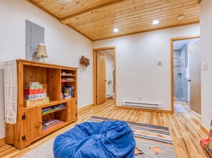 A room with a wooden ceiling, a bookshelf, a blue bean bag, and a shower area. - Sandy Riverfront Retreat • Dogs OK • Ski & Hike (Rhododendron)