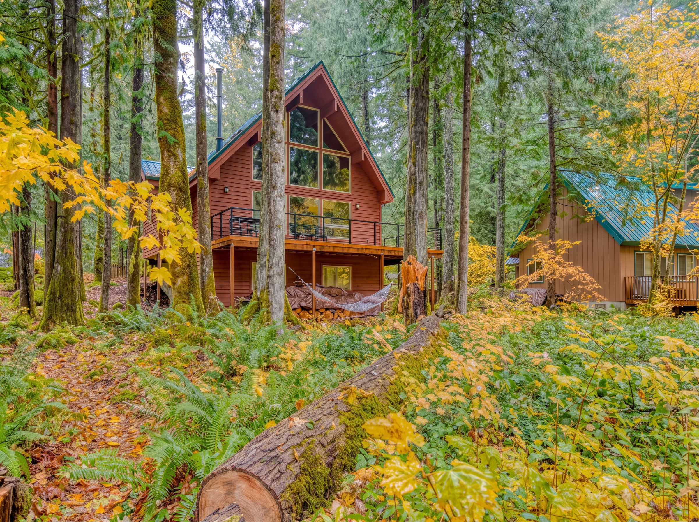 Une cabane dotée d’un balcon, entourée d’une forêt aux couleurs automnales.
