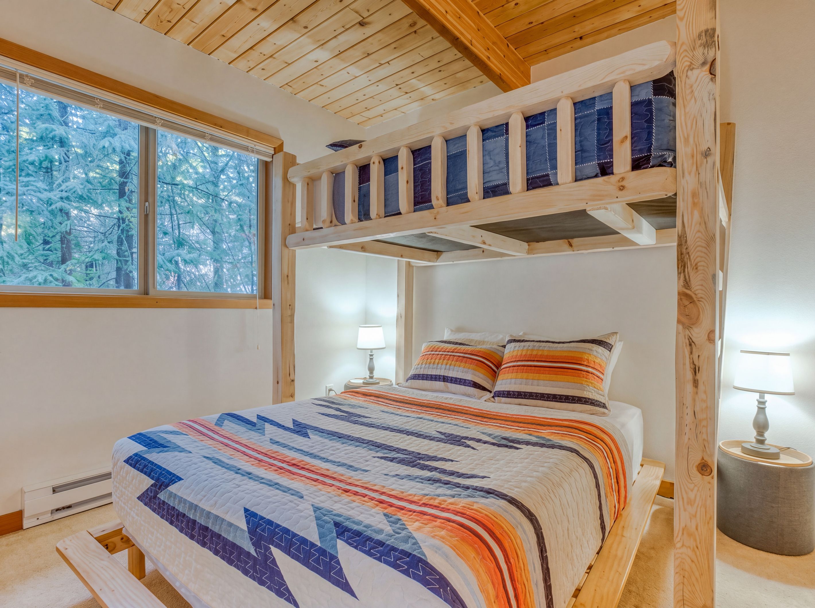 Ein Schlafzimmer mit Etagenbett, großem Fenster und Blick auf schneebedeckte Bäume.