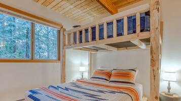 Ein Schlafzimmer mit Etagenbett, großem Fenster und Blick auf schneebedeckte Bäume.
