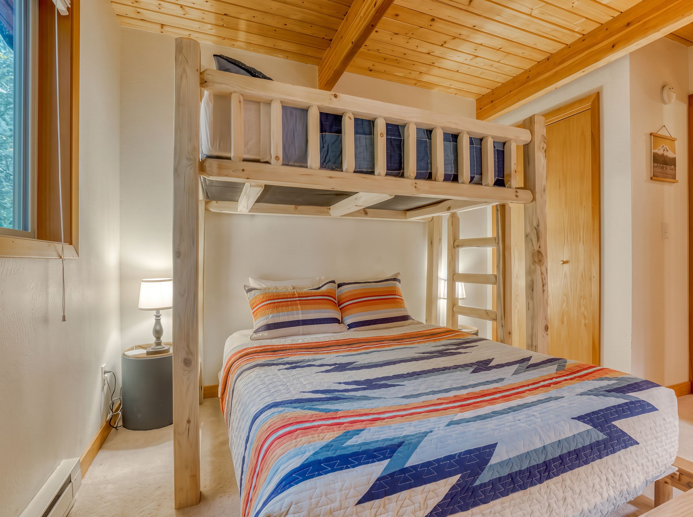 A bunk bed with a wooden frame, a quilted bedspread, and a bedside lamp.