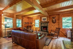 A log cabin interior with a leather sofa, a fireplace, and a deer head mounted on the wall. - Camp Shanahan - Boat Access only camp (Webb)