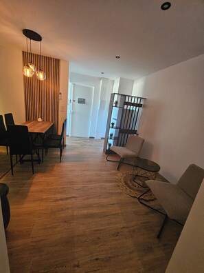 A modern living room with a wooden floor, a dining area with a table and chairs, and a staircase leading to another level. - Comfortable apartment 5 minutes from the train station (Perpignan)