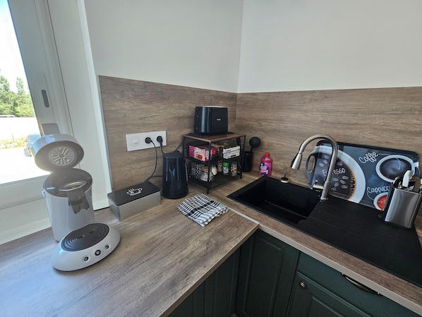 A kitchen with a coffee maker, a kettle, a sink, and a coffee-themed mat. - Comfortable apartment 5 minutes from the train station (Perpignan)