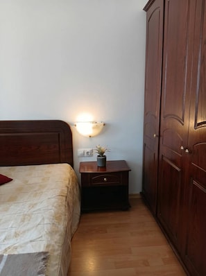 A bedroom with a wooden bed, a bedside table with a lamp, and a wardrobe. - South Facing Balcony 1 BR (Bansko)