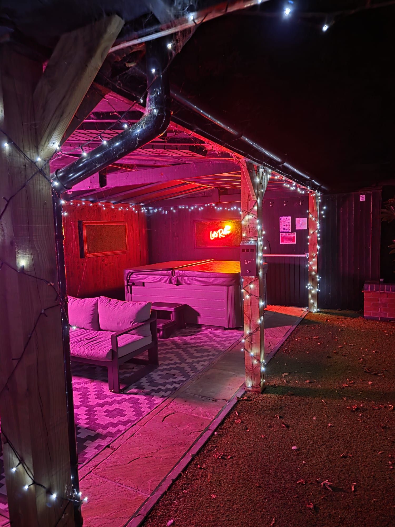 Una habitación con una cama, un letrero de neón y luces colgantes.