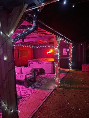 A room with a bed, a neon sign, and string lights.