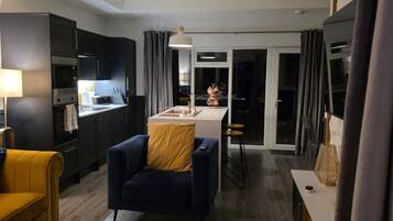 A modern living room with a sofa, a dining area, and a kitchen in the background.