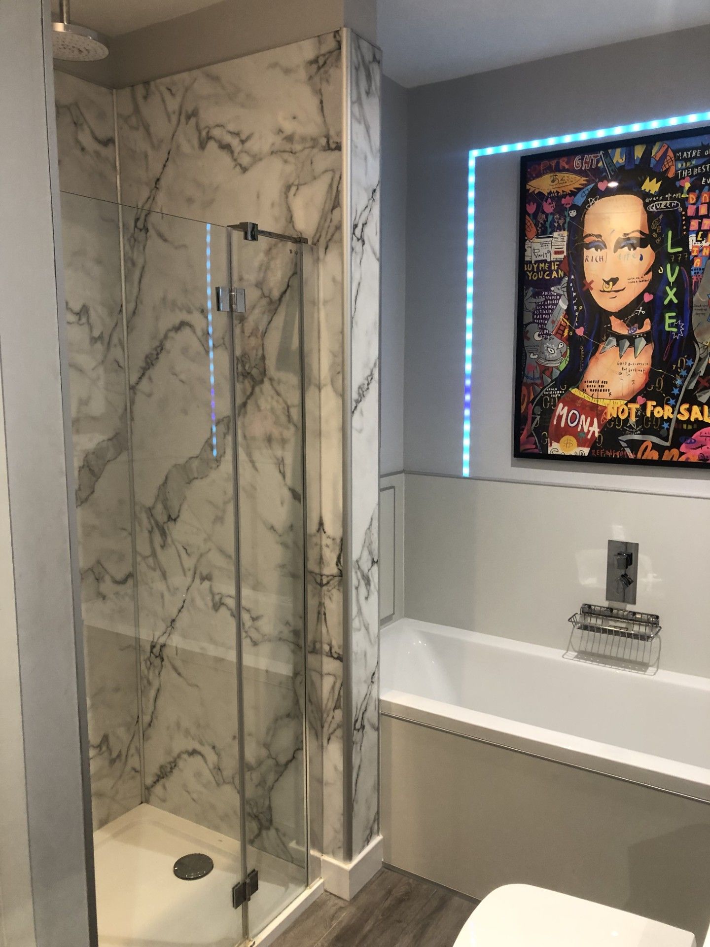 A bathroom with a glass-enclosed shower, a white bathtub, and a wall-mounted mirror.