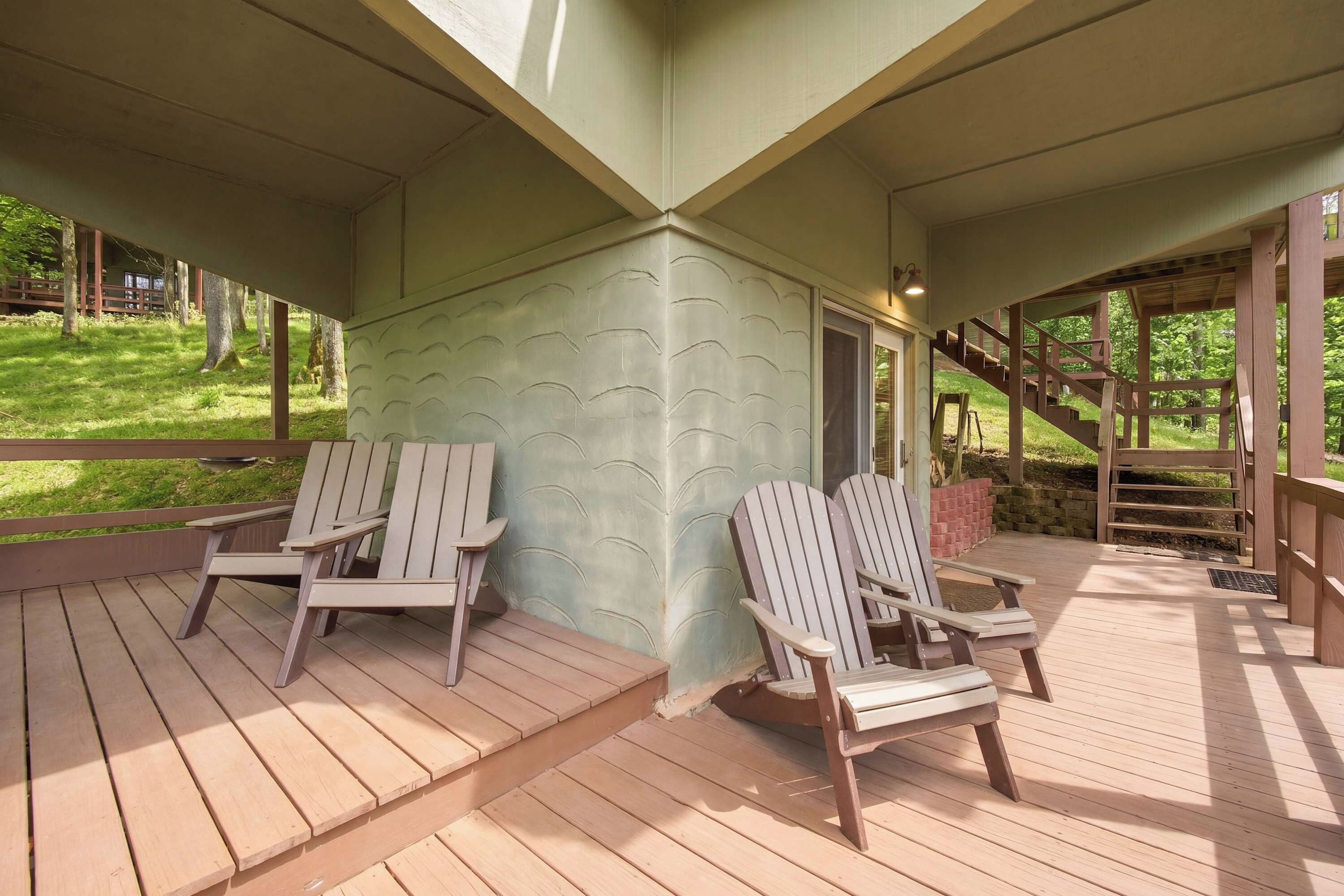 Un espacio al aire libre cubierto con dos sillas Adirondack, una terraza de madera y vistas a un paisaje verde.