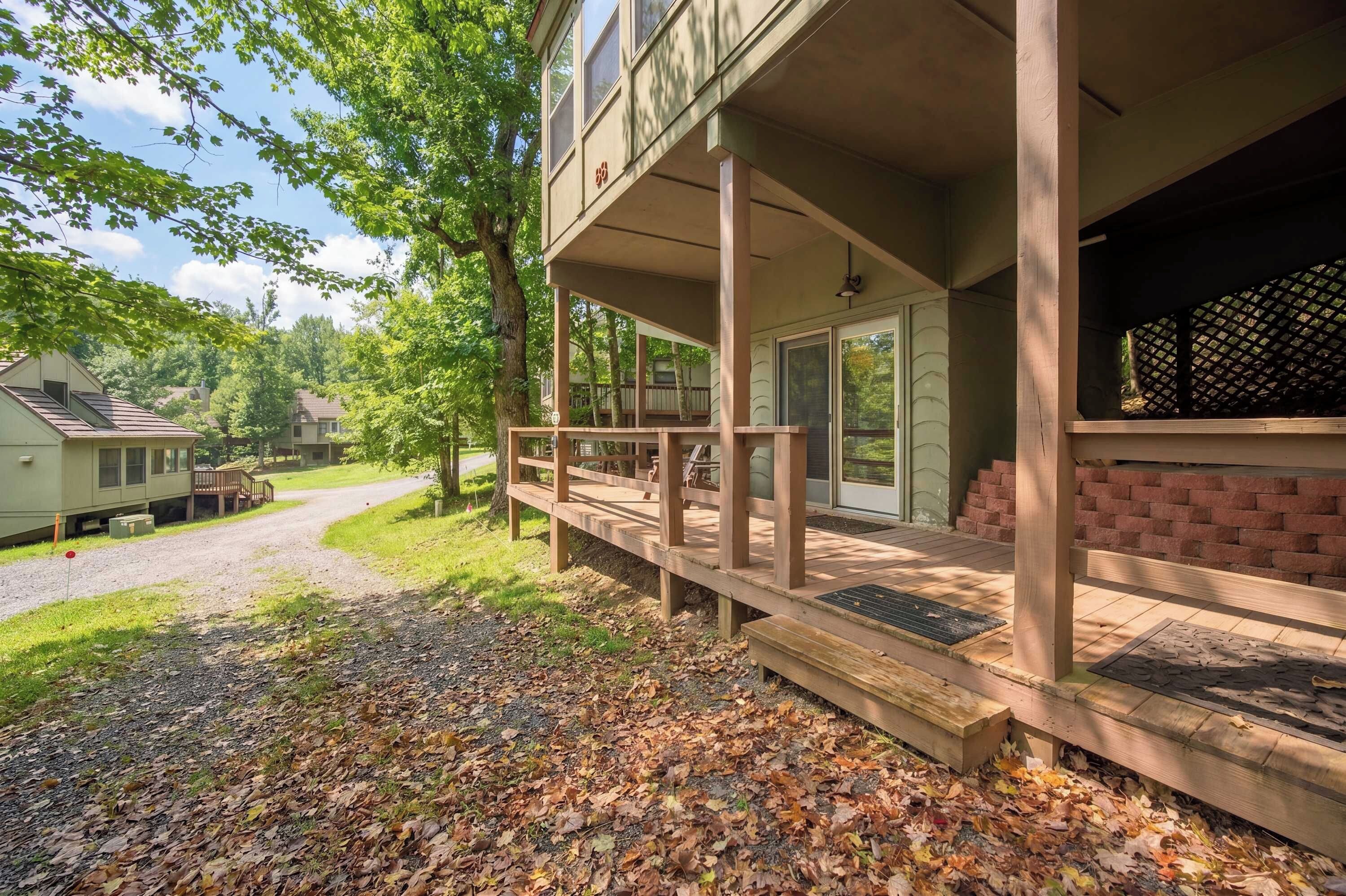 A two-story building with a covered porch, a brick wall, and a gravel driveway.