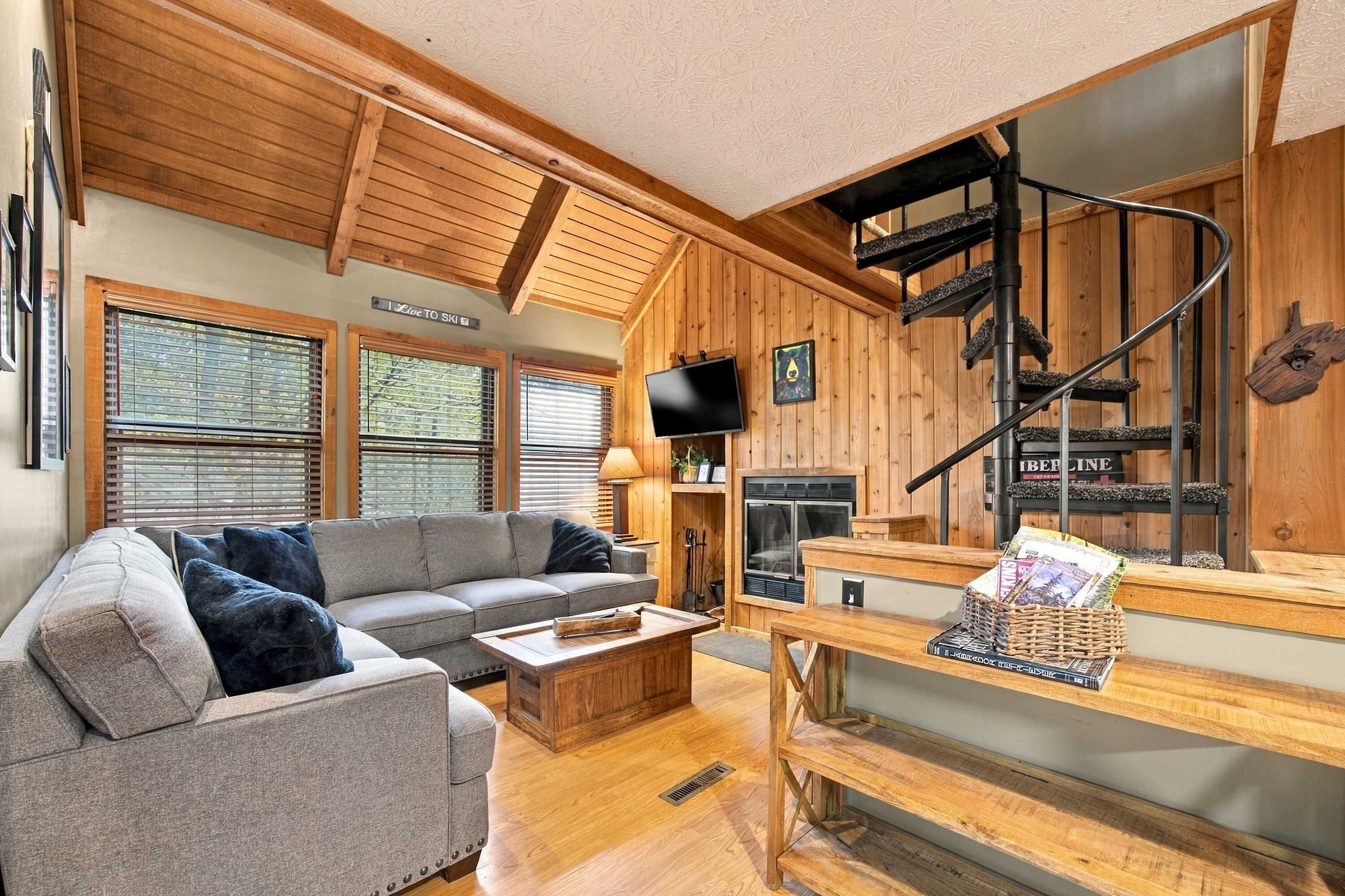 A cozy living room with a grey sofa, a wooden coffee table, and a fireplace.