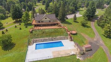 A large house with a swimming pool, surrounded by a well-maintained lawn and trees.