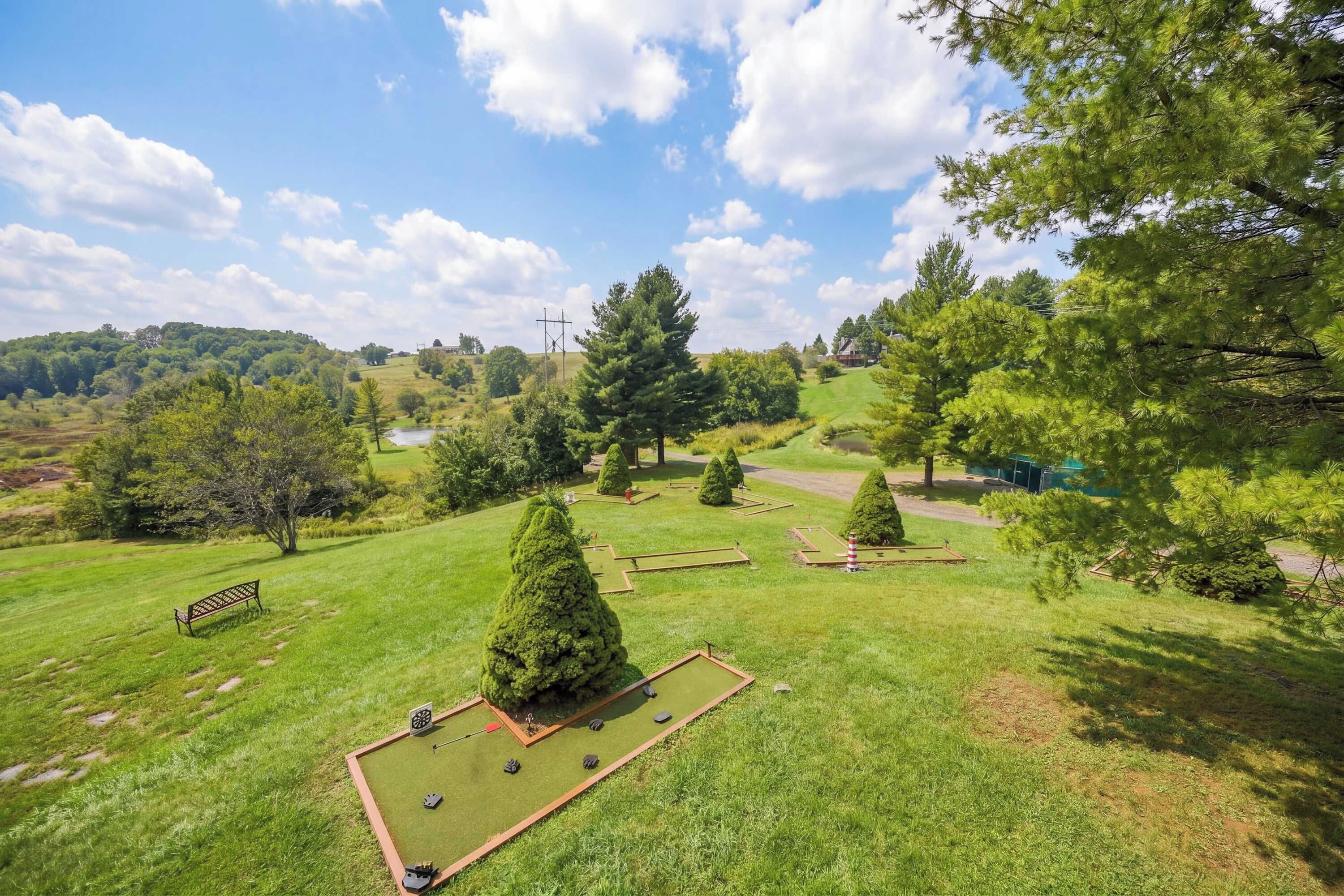 A well-maintained park with a lawn, a bench, and neatly trimmed trees.