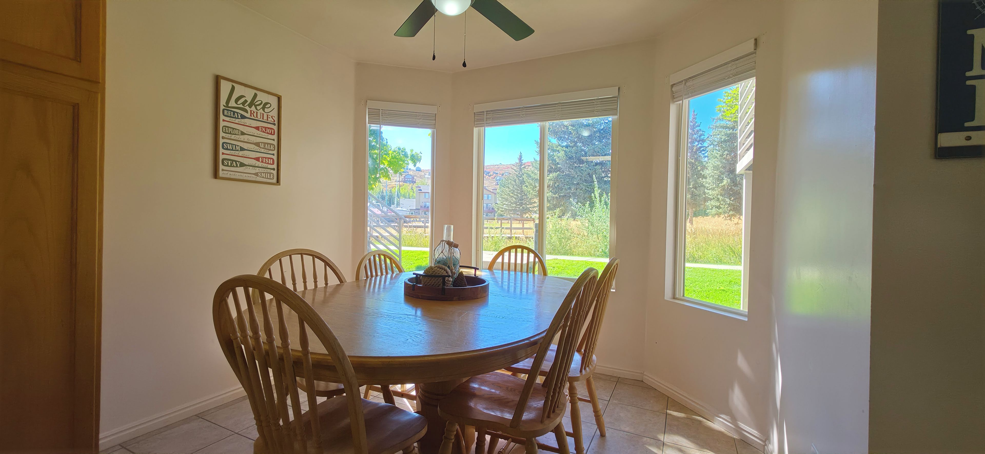 A dining area with a round table, wooden chairs, and a ceiling fan.