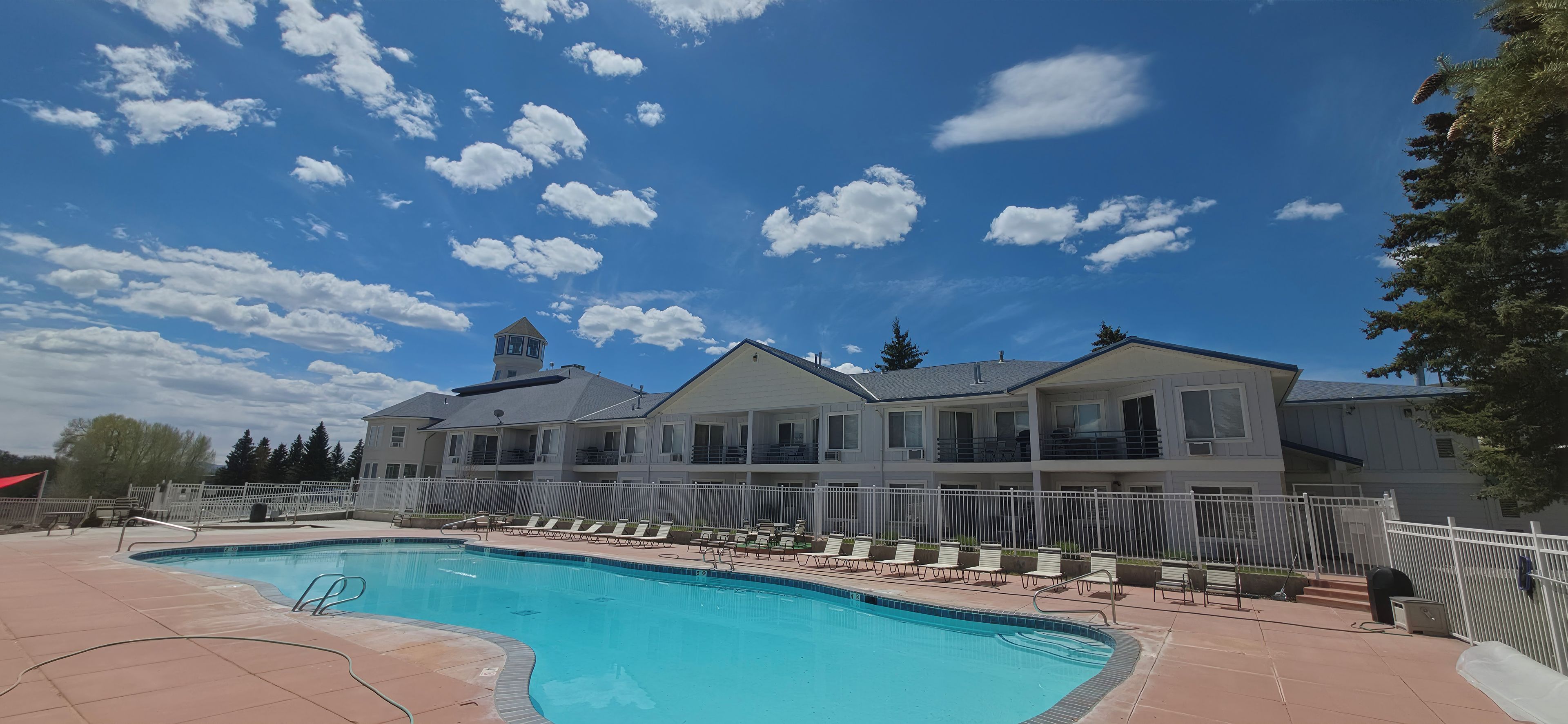 A swimming pool with lounge chairs and a building with multiple balconies.