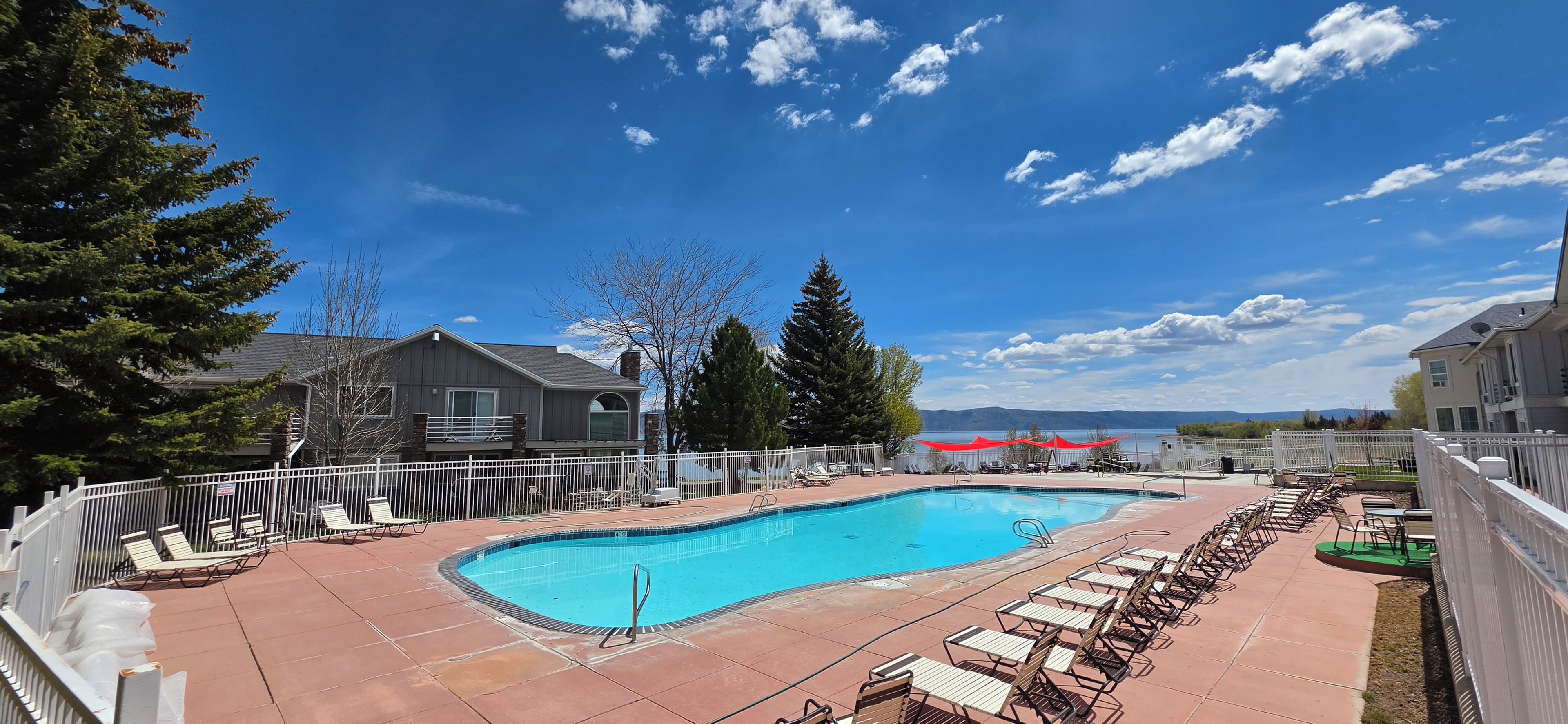 Sunny outdoor pool with lounge chairs and scenic water-view backdrop