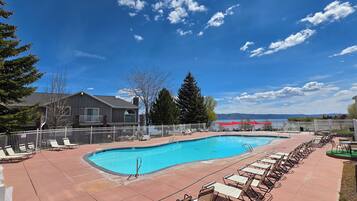 Sunny outdoor pool with lounge chairs and scenic water-view backdrop