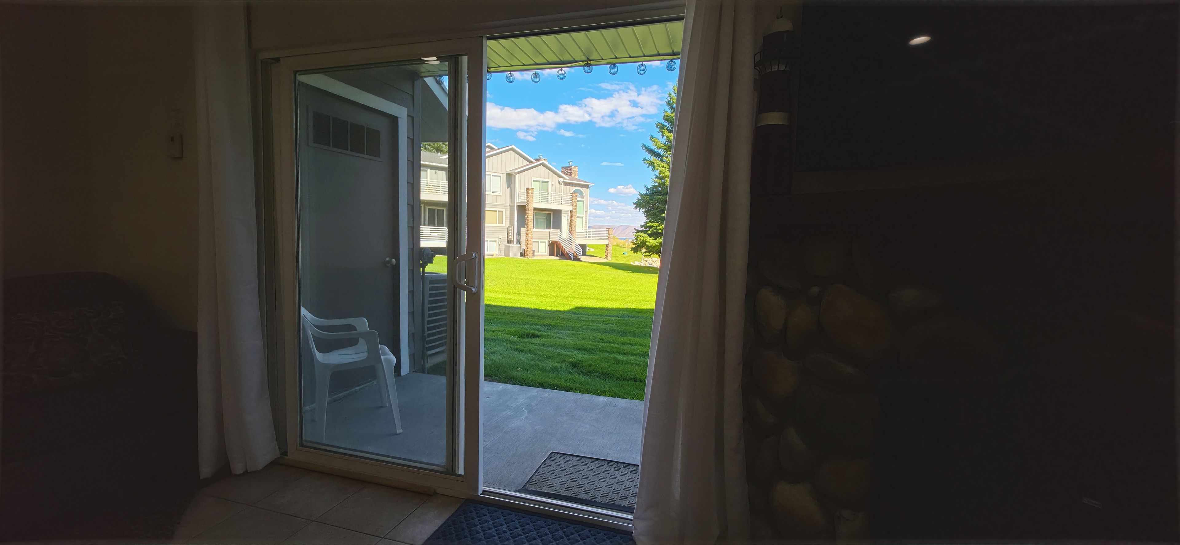 A sliding glass door leading to a grassy yard with a house in the background.