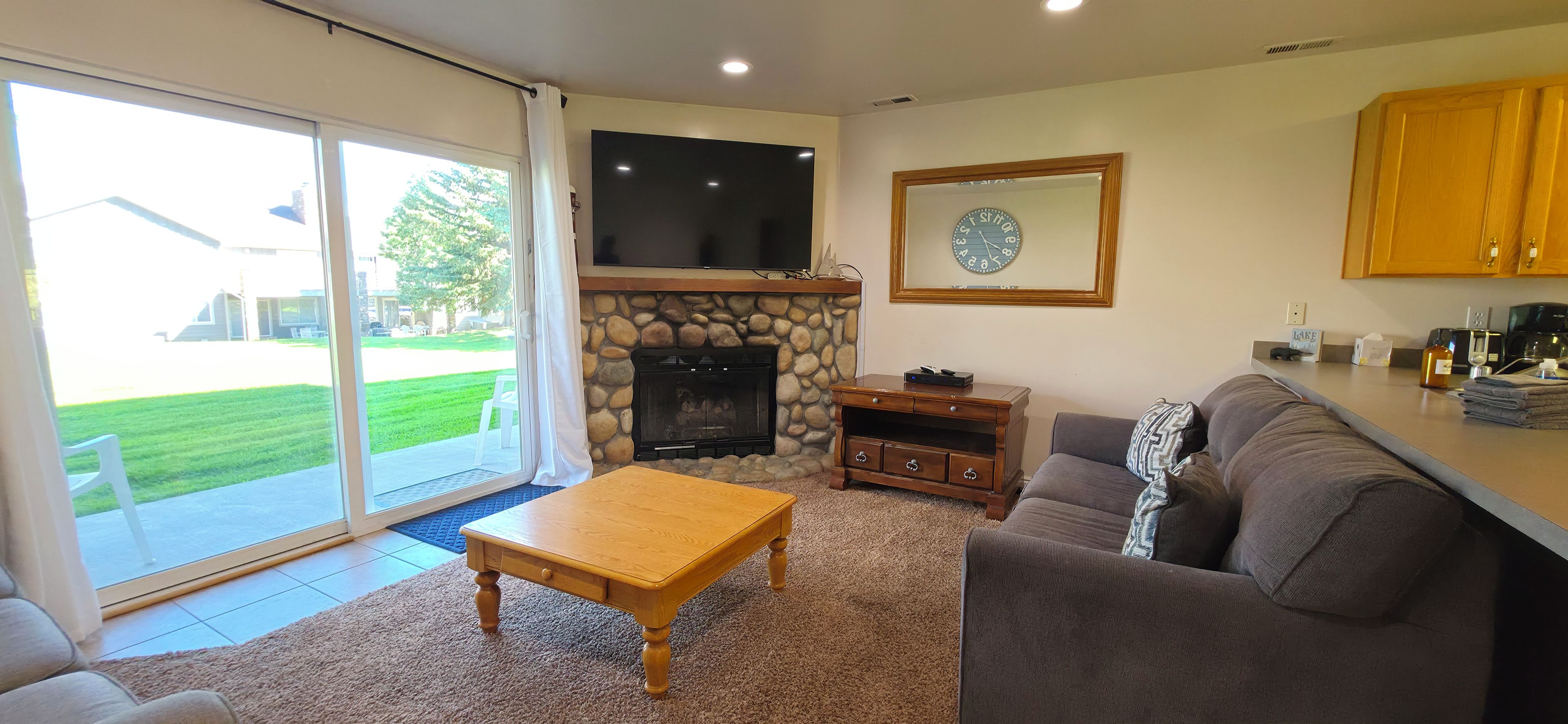 Cozy living room with stone fireplace, big TV, and patio access