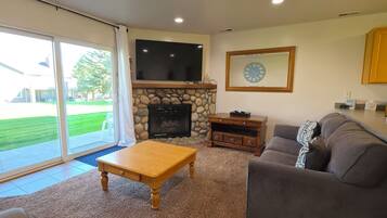 Cozy living room with stone fireplace, big TV, and patio access