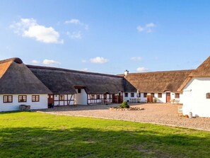 A traditional building with a thatched roof, white walls, and a gravel courtyard. - 6 Person Holiday Home in Blavand (Blavand)