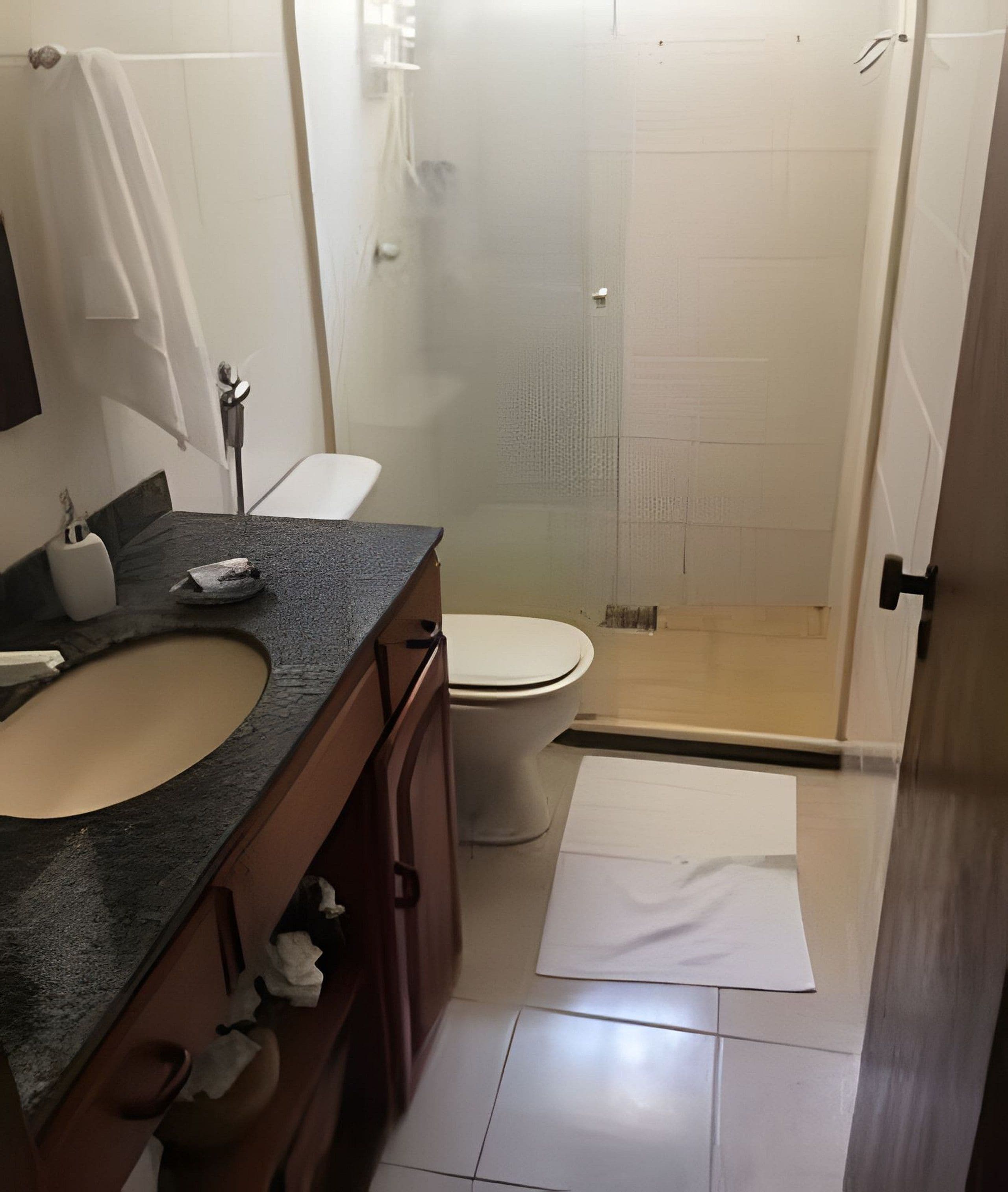 A bathroom with a sink, toilet, and shower area.