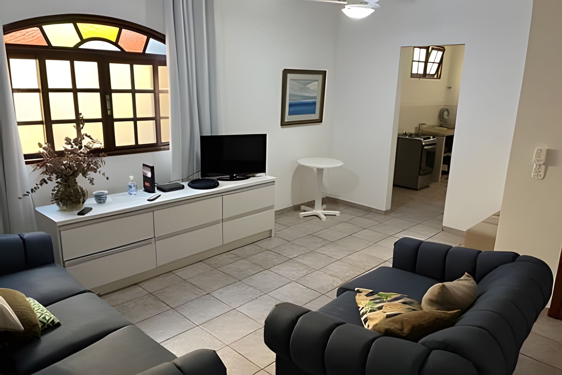 A modern living room with a sofa, a small table, a TV, and a potted plant.