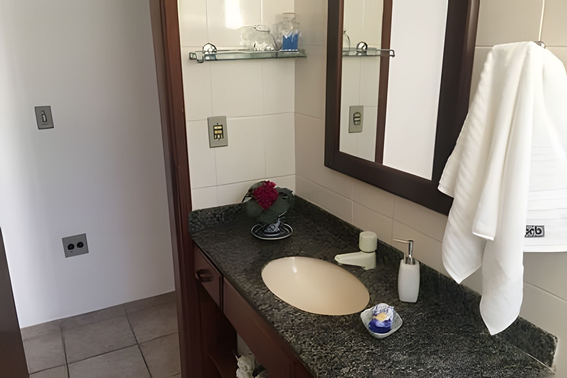 A bathroom with a sink, mirror, towel rack, and toiletries.