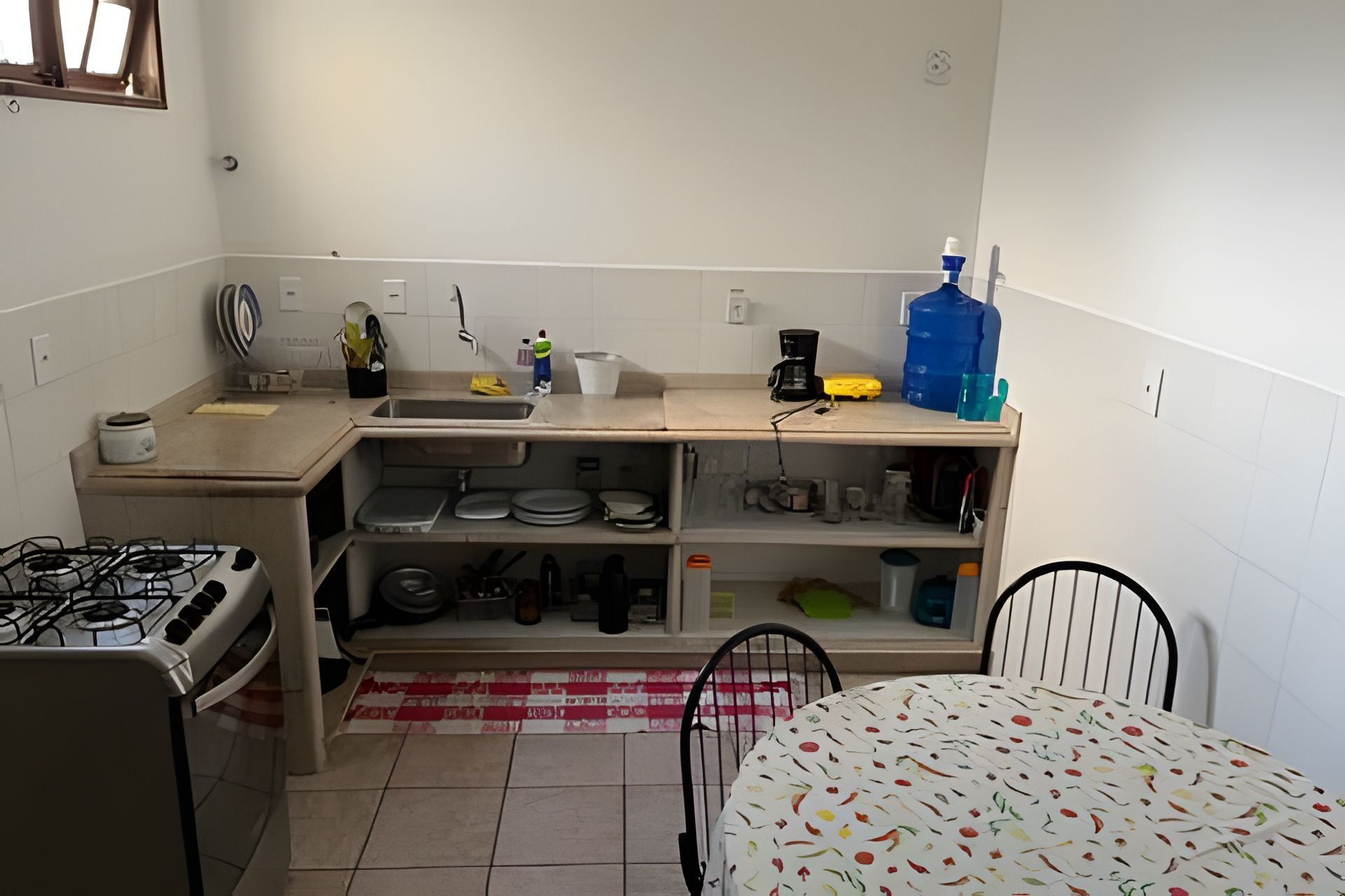 Una cocina compacta con estufa a gas, pileta y distintos utensilios de cocina.