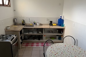 A compact kitchen with a gas stove, sink, and various kitchen utensils.