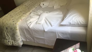En säng med vita lakan och en pläd med blommönster.