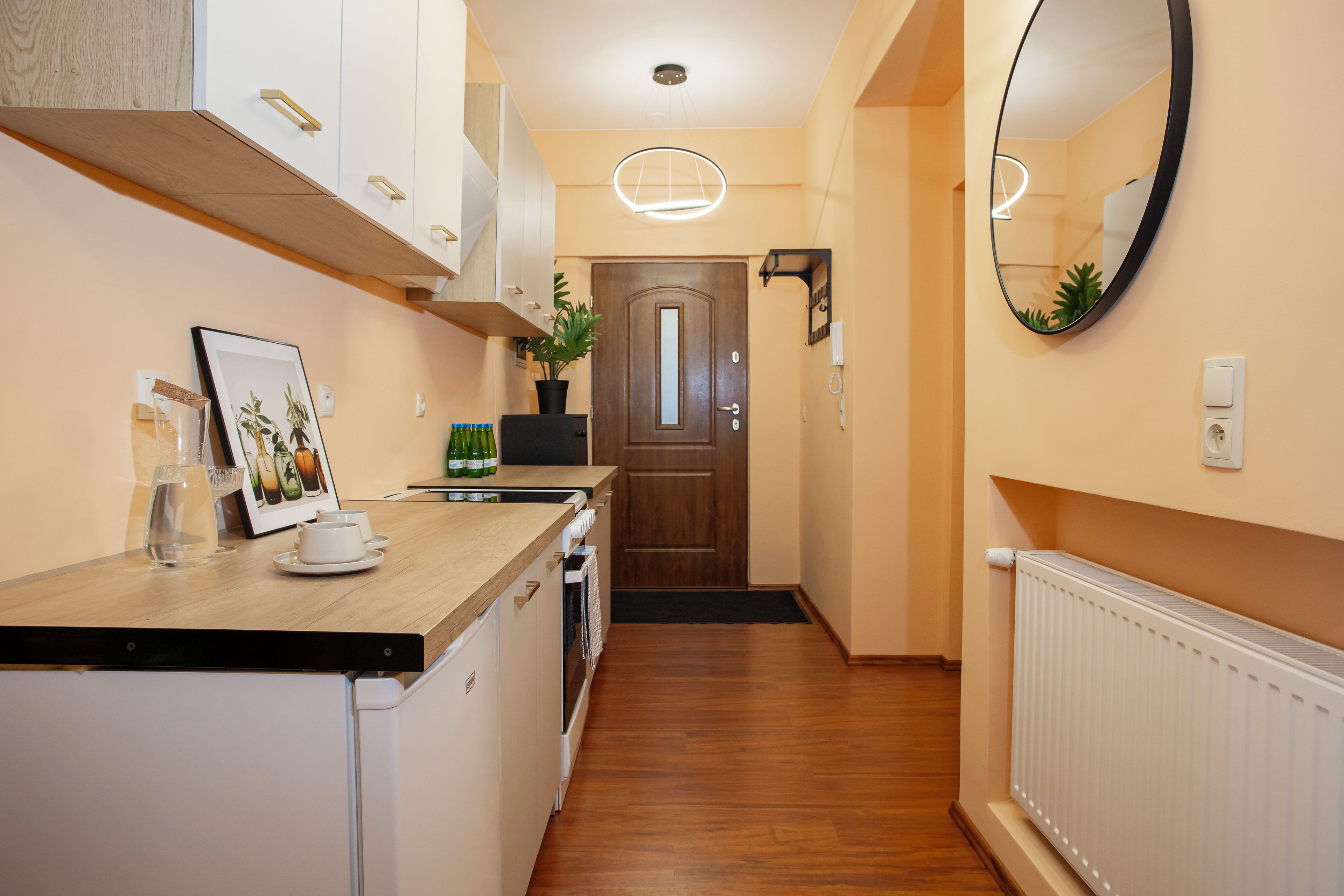 A narrow kitchen with wooden cabinets, a countertop, and a door leading to another room.