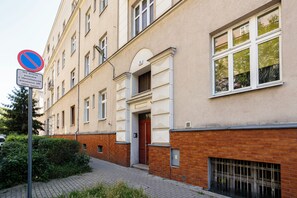 A multi-story building with a brick facade, a no parking sign, and a door with a security keypad. - Słoneczny Apartament - P. Wilsona i MTP (Poznań)