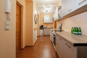 A modern kitchen with wooden cabinets, a built-in oven, and a coffee maker. - Słoneczny Apartament - P. Wilsona i MTP (Poznań)