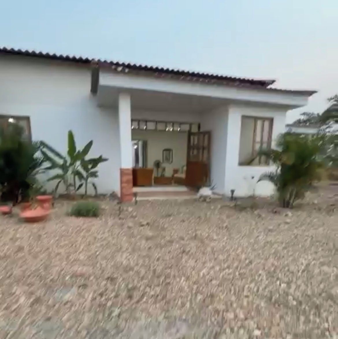 A house with a tiled roof, a porch, and potted plants.