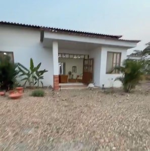 Una casa con techo de tejas, un porche y plantas en macetas.