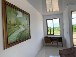 A room with a desk, chair, and a large painting of a landscape. - Casa Blanca Estate, Puerto Lopez (Meta)