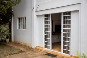 Ein weißes Gebäude mit Schiebetür, kleinem Fenster und einer Topfpflanze.