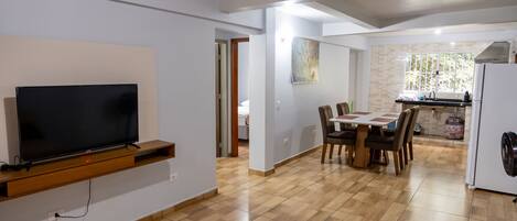 Una cocina moderna con zona de comedor, televisor de pantalla plana en la pared y refrigerador.