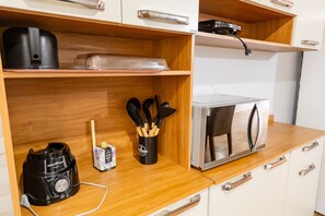 Une petite cuisine équipée d’une machine à café, d’un grille-pain et d’un ensemble de couteaux rangés dans un porte-couteaux.
