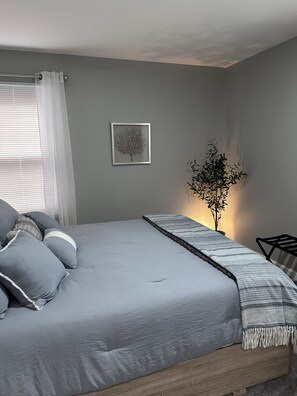 A bedroom with a bed, a bedside table, a lamp, and a framed picture on the wall.