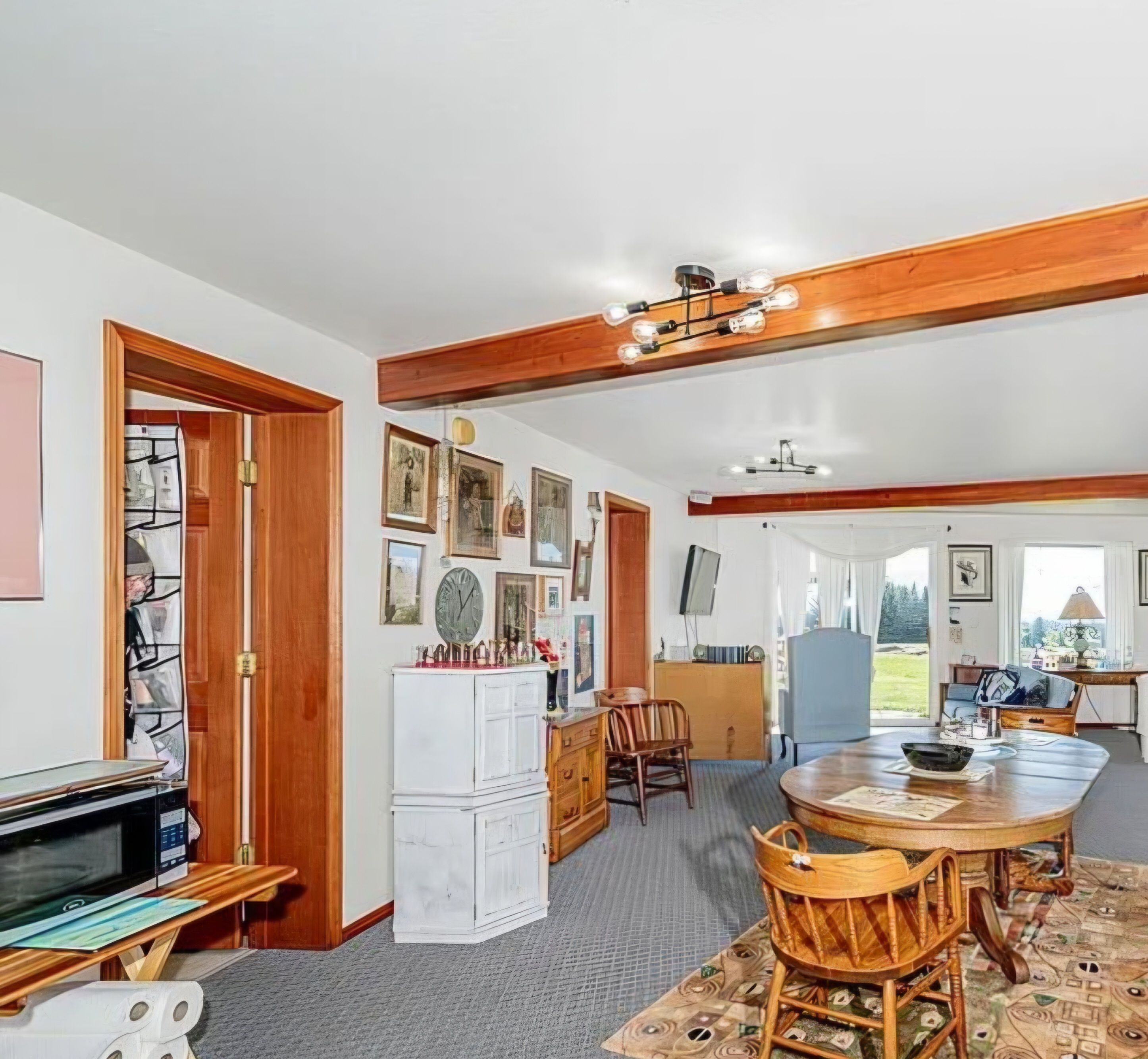 A spacious room with a dining table, chairs, a white cabinet, and a television.