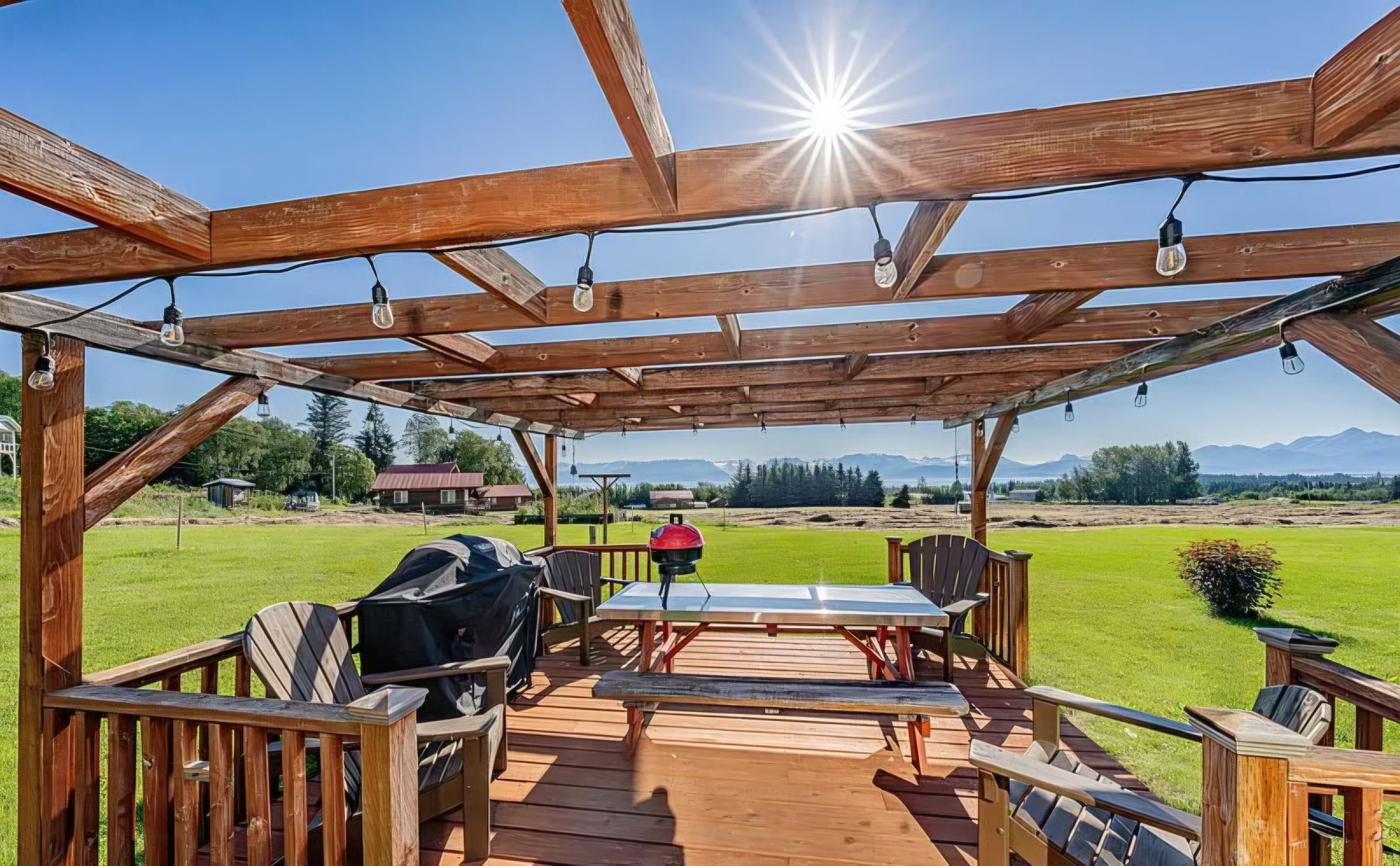 A wooden deck with a pergola, outdoor furniture, and a grill.