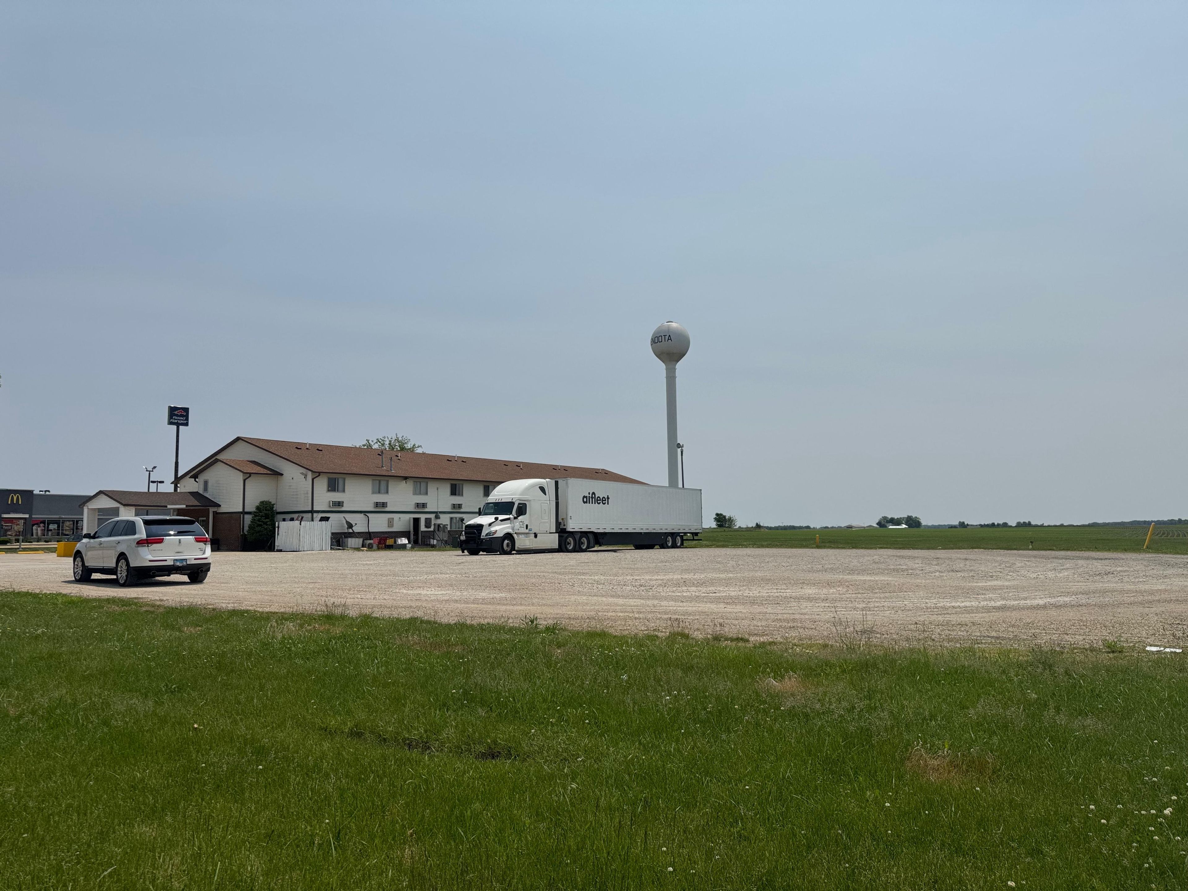 A building with a large water tower, a white truck, and a car parked in front.
