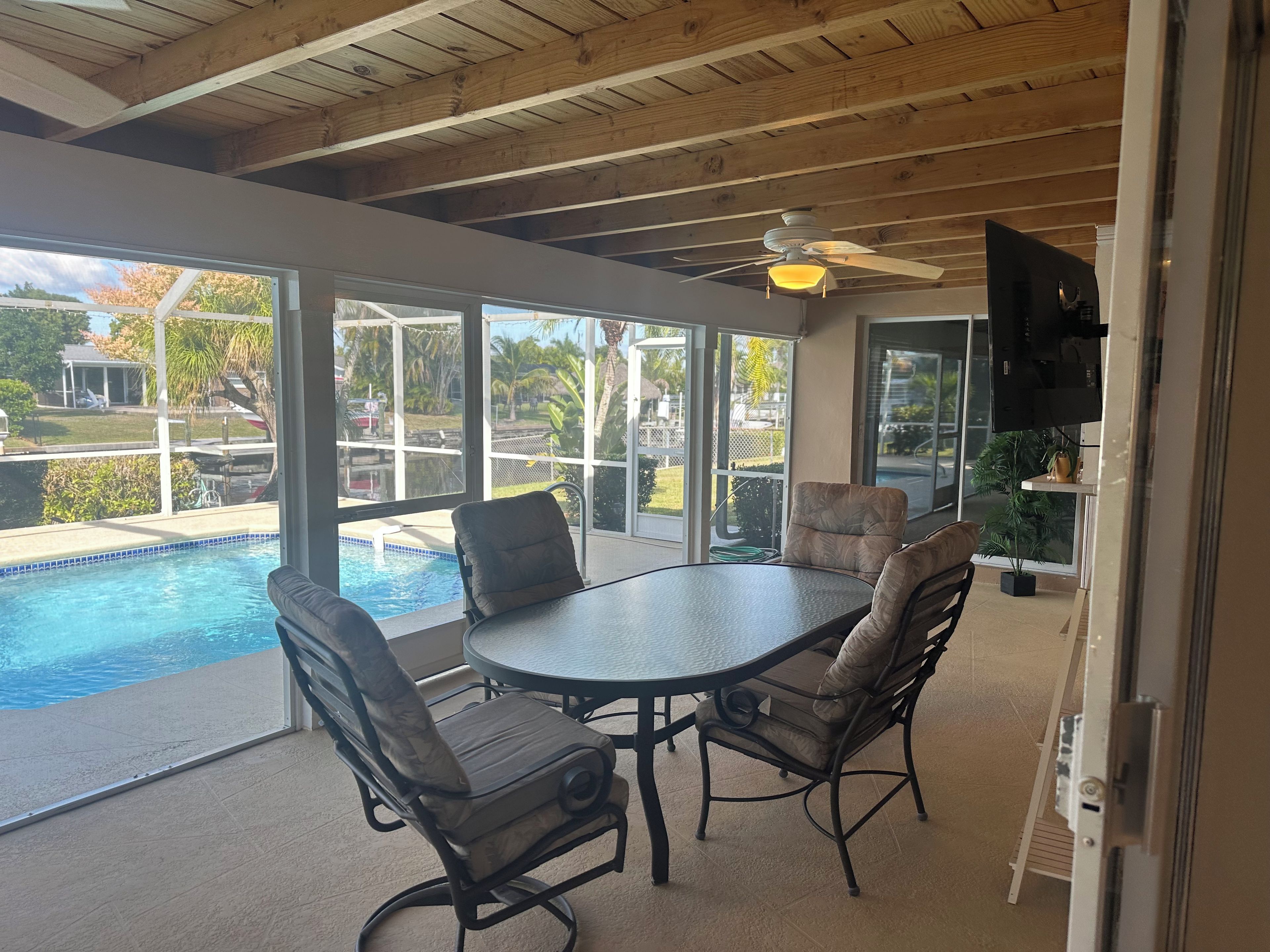 A covered patio with a pool, a table, and chairs.