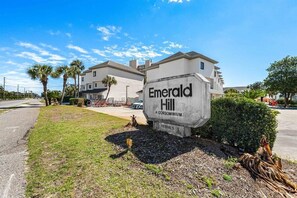A sign for Emerald Hill Condominium with a clear view of the surrounding buildings and a well-maintained lawn. - Emerald Hill 21 (Santa Rosa Beach)