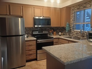 A kitchen with stainless steel appliances, wooden cabinets, and a granite countertop. - Peaceful Laughlin Oasis - First Floor- No Stairs (Laughlin)